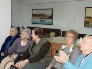 Τρόφιμοι κάθονται και παρακολουθούν τη γιορτή στο ευγηρείο, 2018