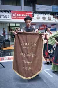 Χορευτές του Λαϊκού Εργαστηρίου Πάτρας με πανό στην παρέλαση, 2019