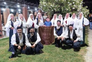 Χορευτές του Λαϊκού Εργαστηρίου Πάτρας σε ομαδική φωτογραφία με το πανό της ομάδας, 2024