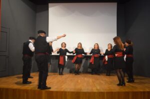 Χορευτές του Λαϊκού Εργαστηρίου Πάτρας σε παραδοσιακό χορό στη σκηνή, 2024